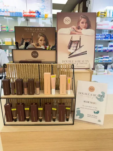 Exhibición de cosméticos con tubos y cajas en estantes, con envases en tonos beige y marrón en una tienda.