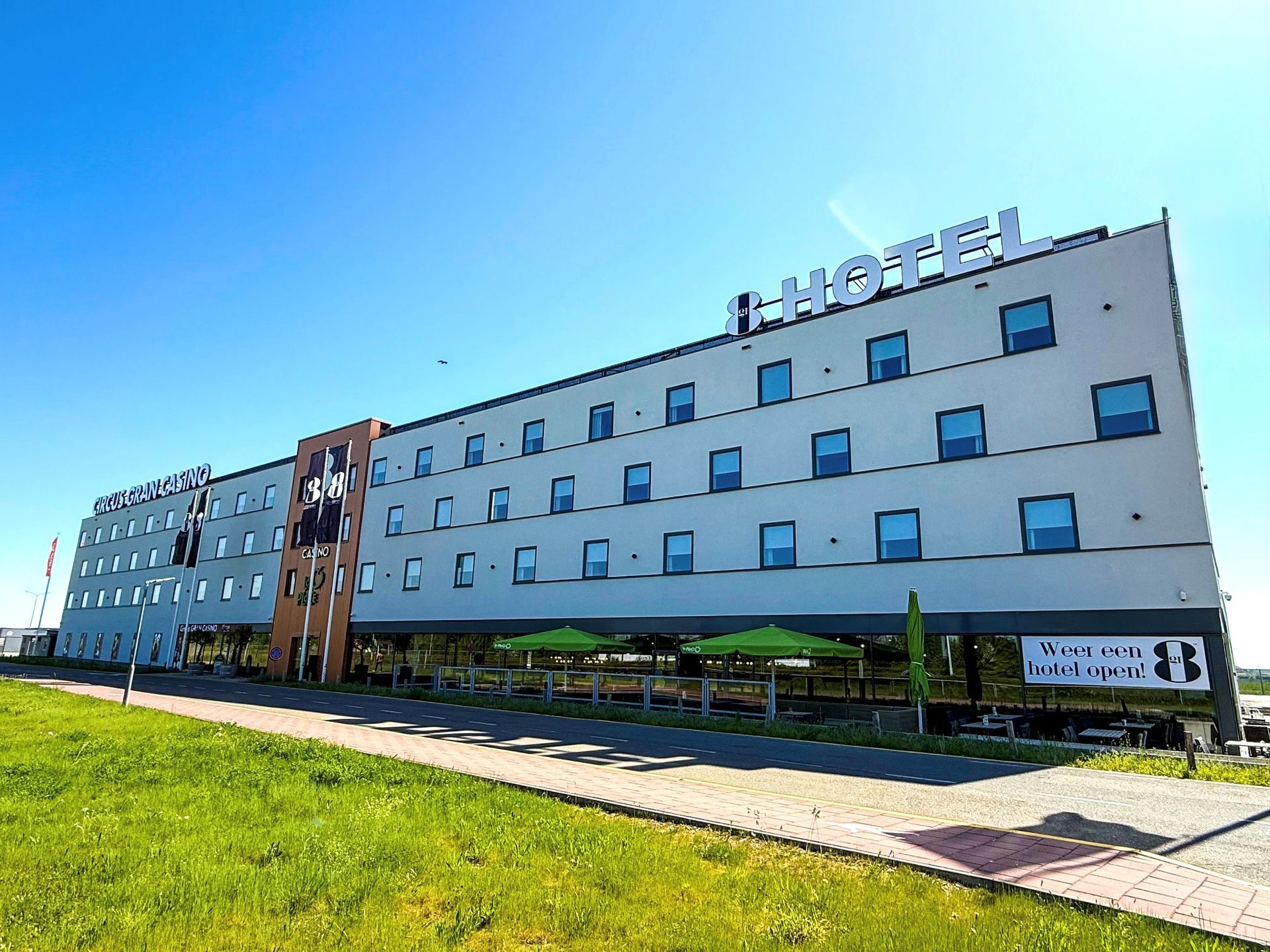Hotel exterior on a sunny day with green grass and a blue sky.