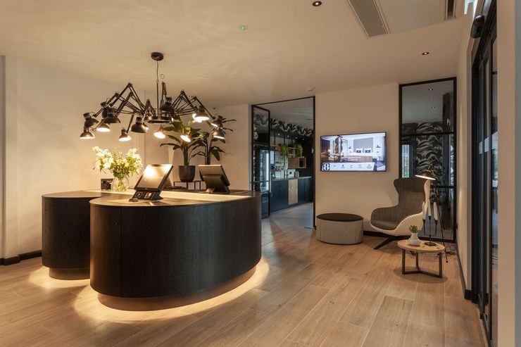Hotelreceptie met een donkerhouten balie, moderne verlichting, een tv en zitgelegenheid.