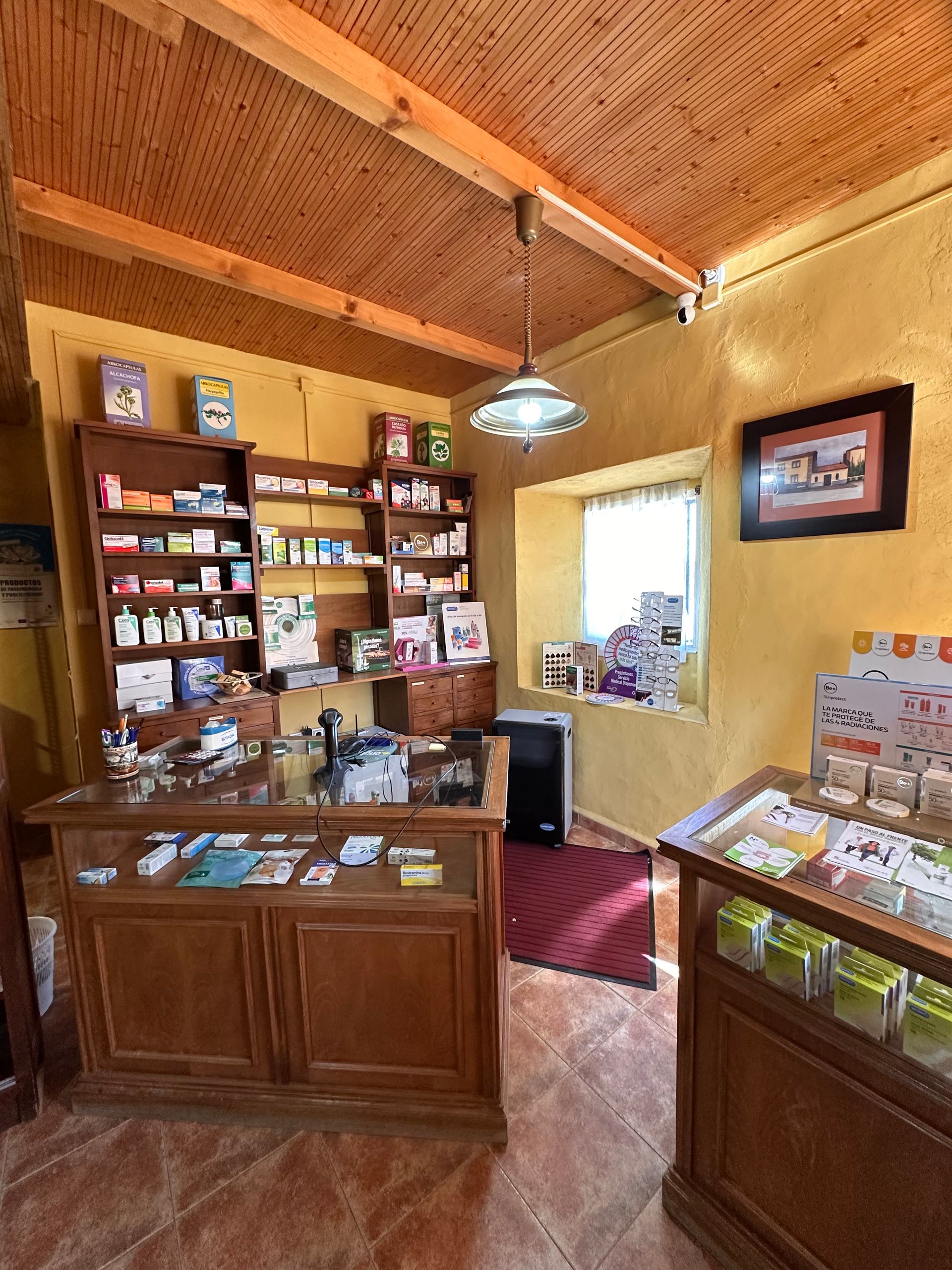 Una farmacia con mostrador de madera, estantes y ventana.