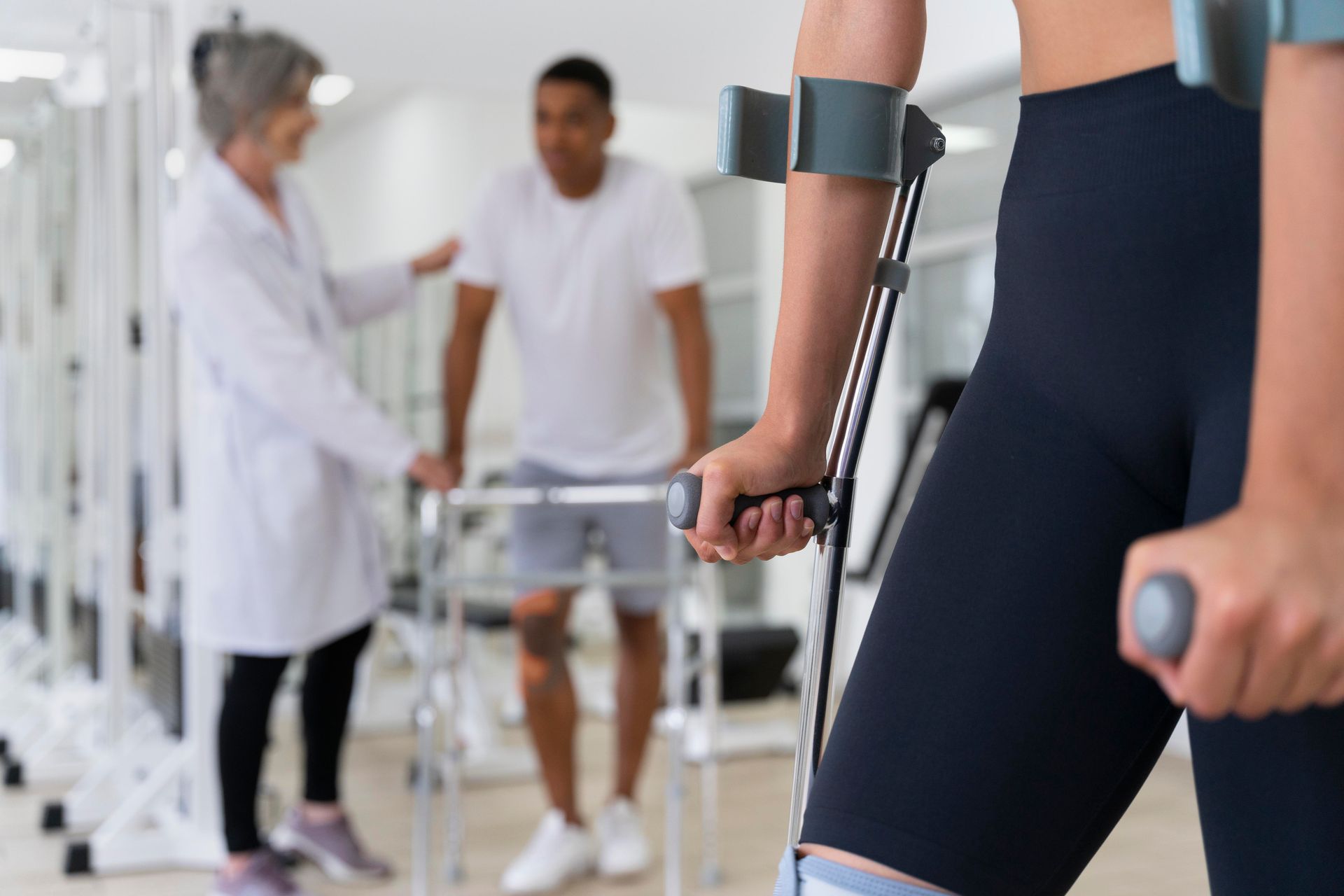 Una mujer con muletas está de pie junto a un hombre con un andador.