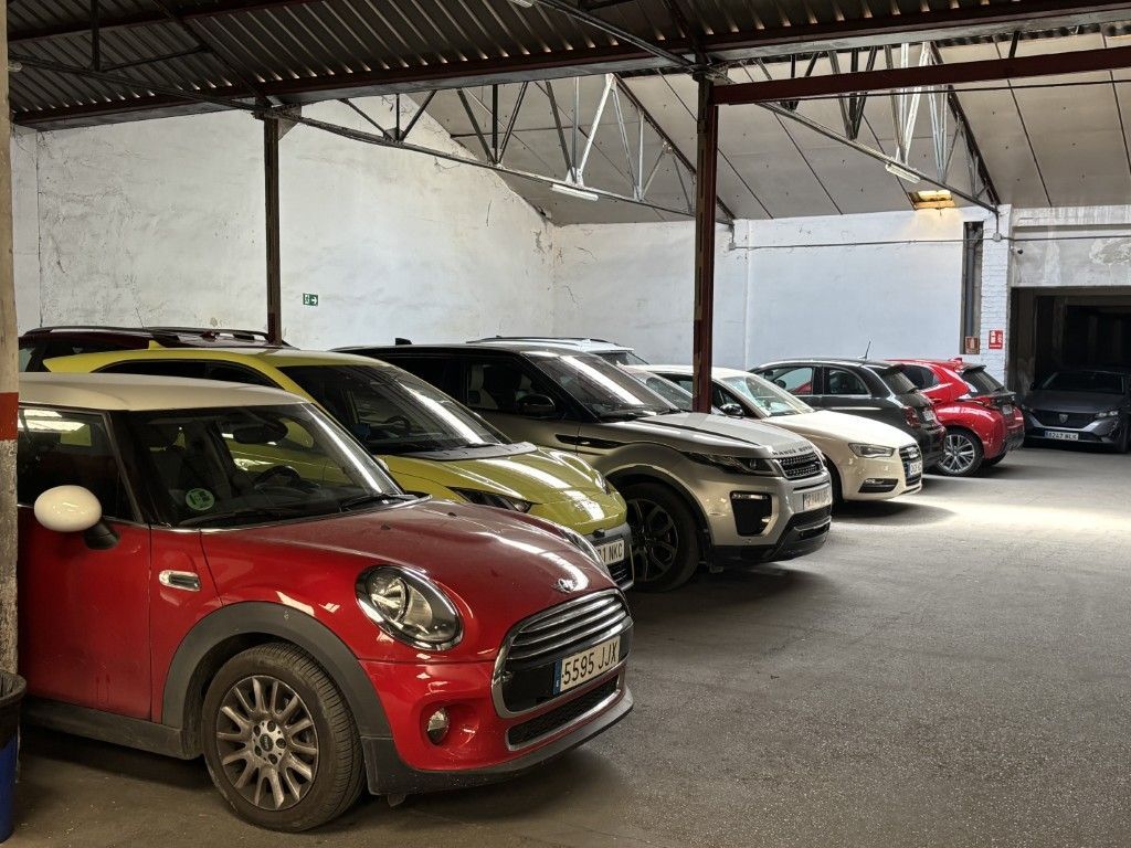 Aparcamiento subterráneo con coches a ambos lados, un cartel de prohibido el paso en la parte superior.