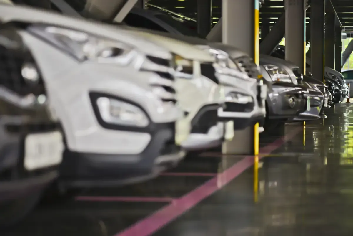 Filas de coches aparcados en un garaje interior reluciente, con un SUV blanco en primer plano.