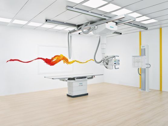Ein digitales Röntgensystem mit deckenmontierter Röntgenröhre, Patiententisch und Wandstativ in einem modernen Behandlungsraum.