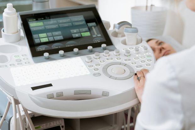 Ein medizinischer Fachmann bedient ein Ultraschallgerät bei der Untersuchung eines Patienten in einer klinischen Umgebung.