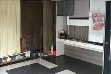 Un interior de cocina moderno con una larga encimera blanca, armarios grises y baldosas con un estampado geométrico.