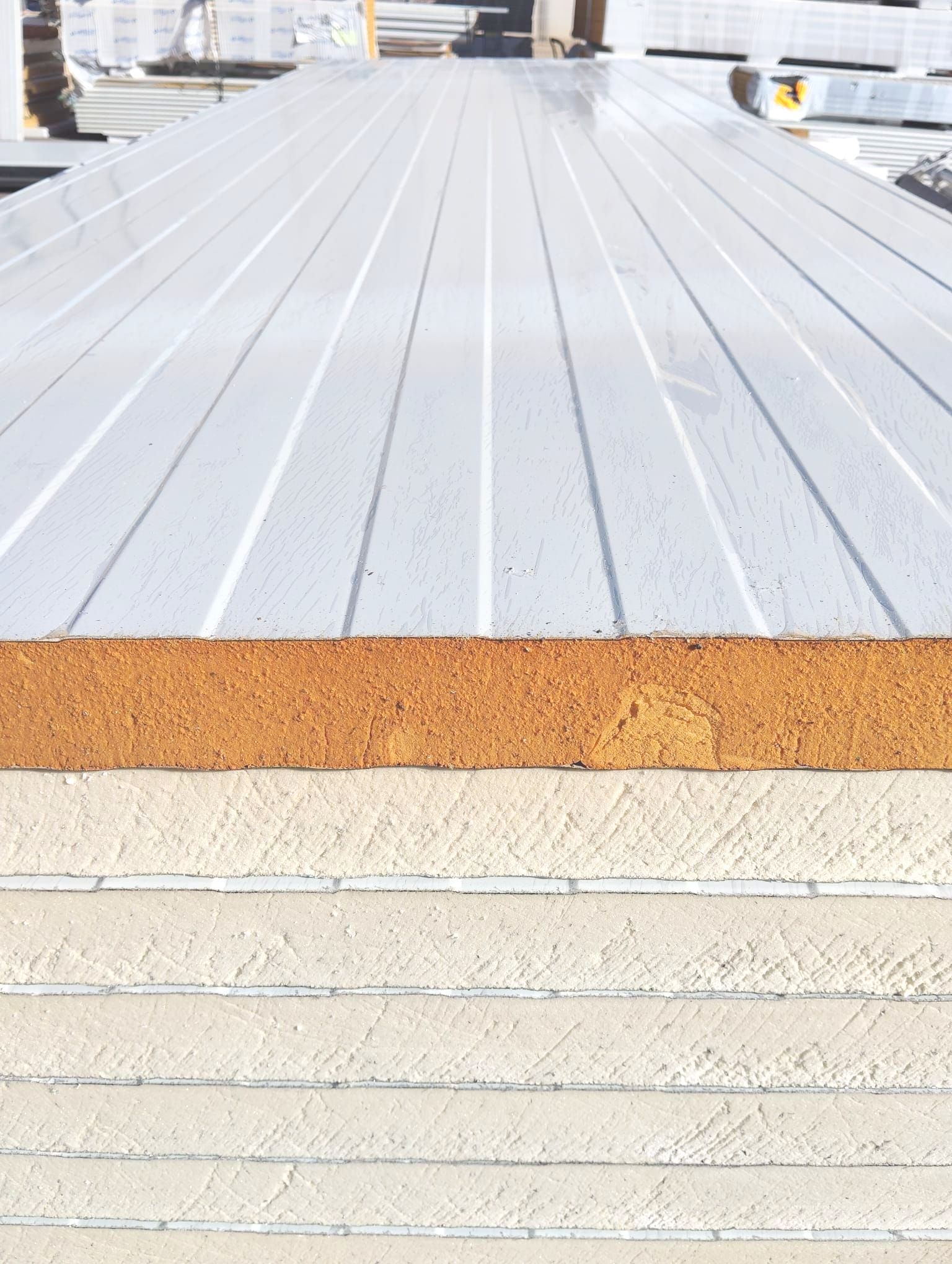 Una grúa está levantando una pared blanca con un cielo azul de fondo.