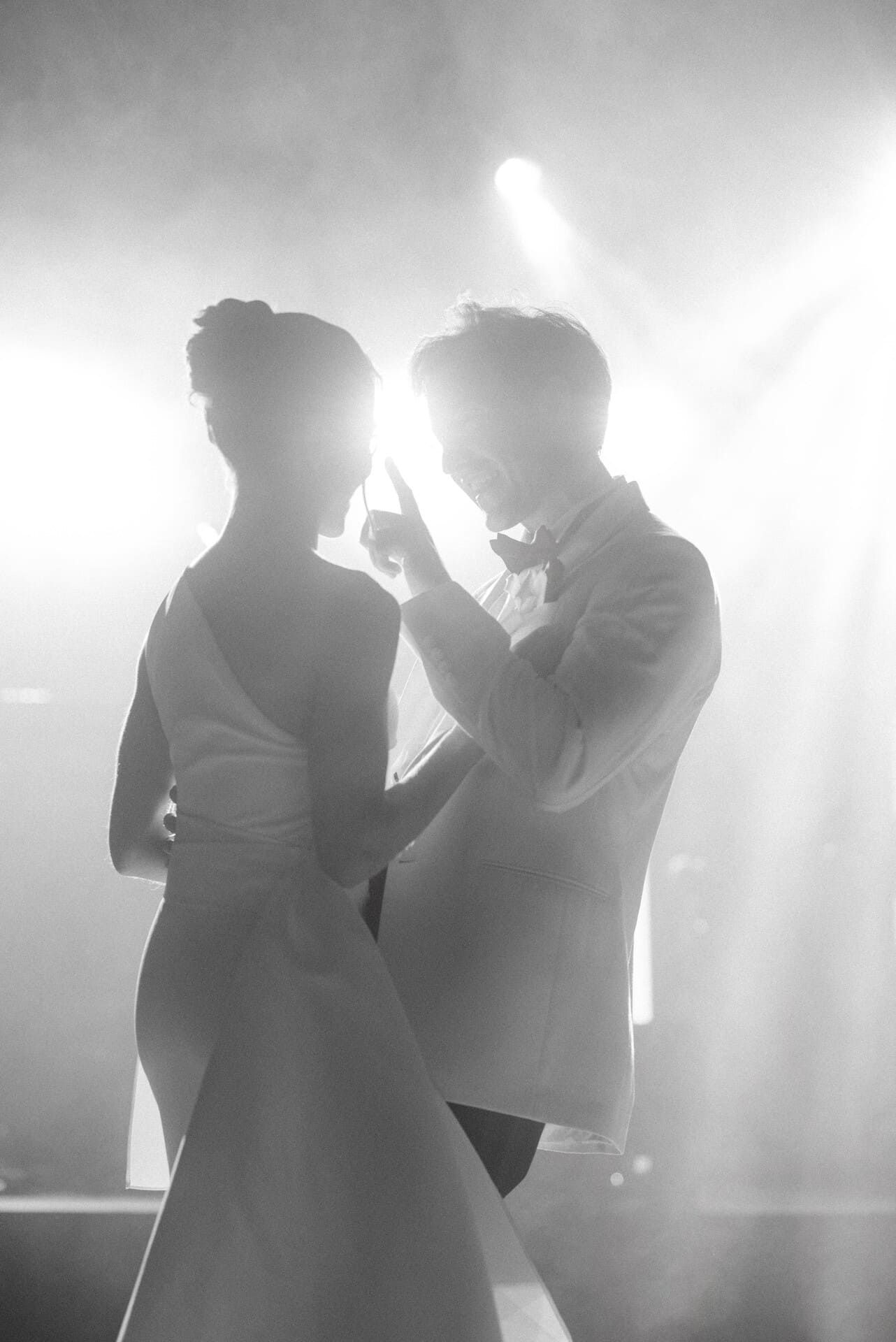 Los recién casados ​​bailan en silueta, iluminados por brillantes luces del escenario.