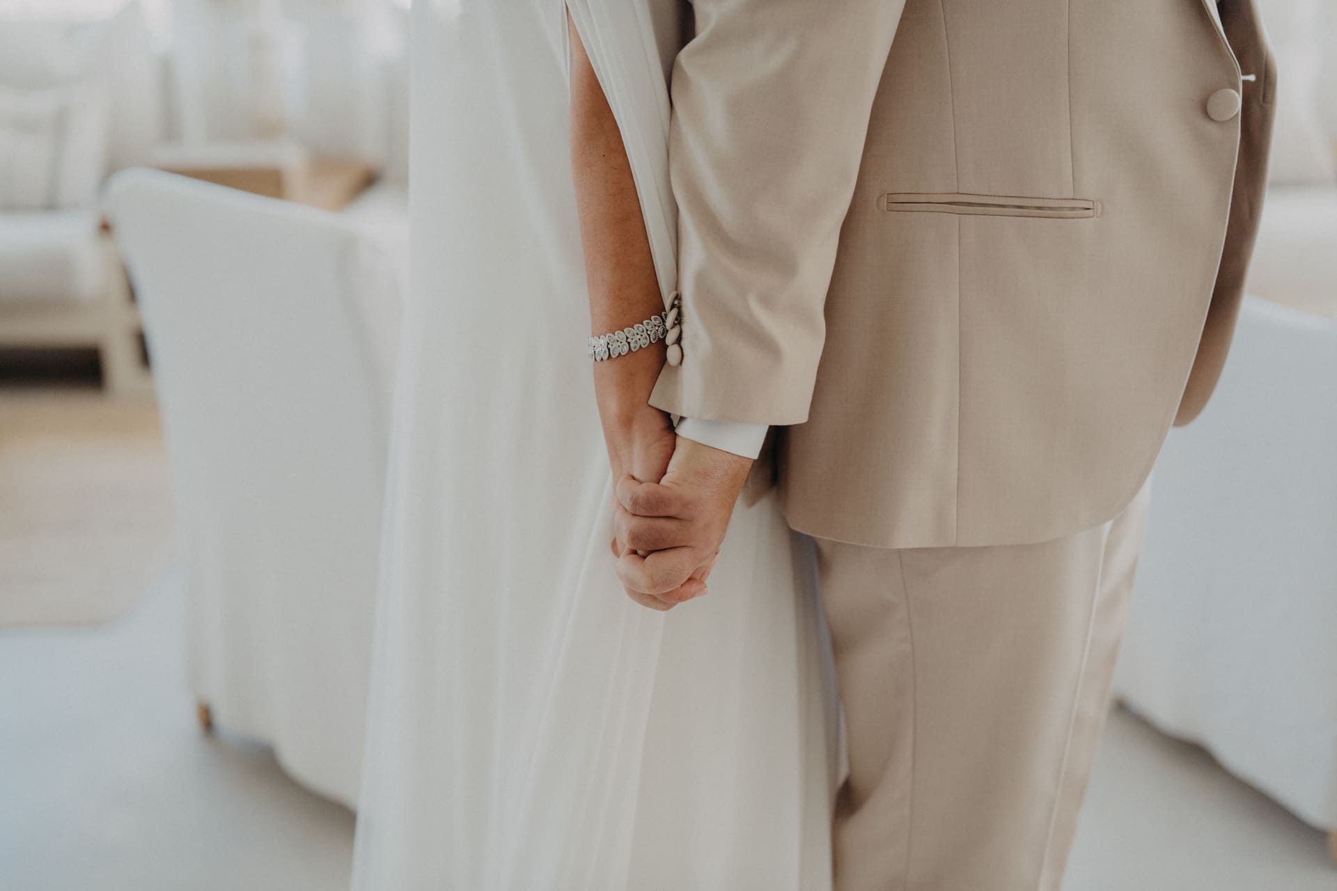 Pareja tomada de la mano durante una ceremonia de boda, la novia de blanco, el novio de bronceado, en el interior.
