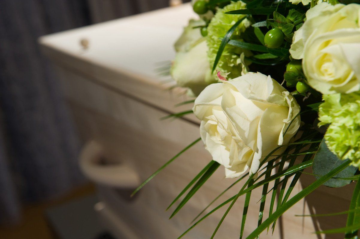 Roses blanches sur un cercueil en bois blanc