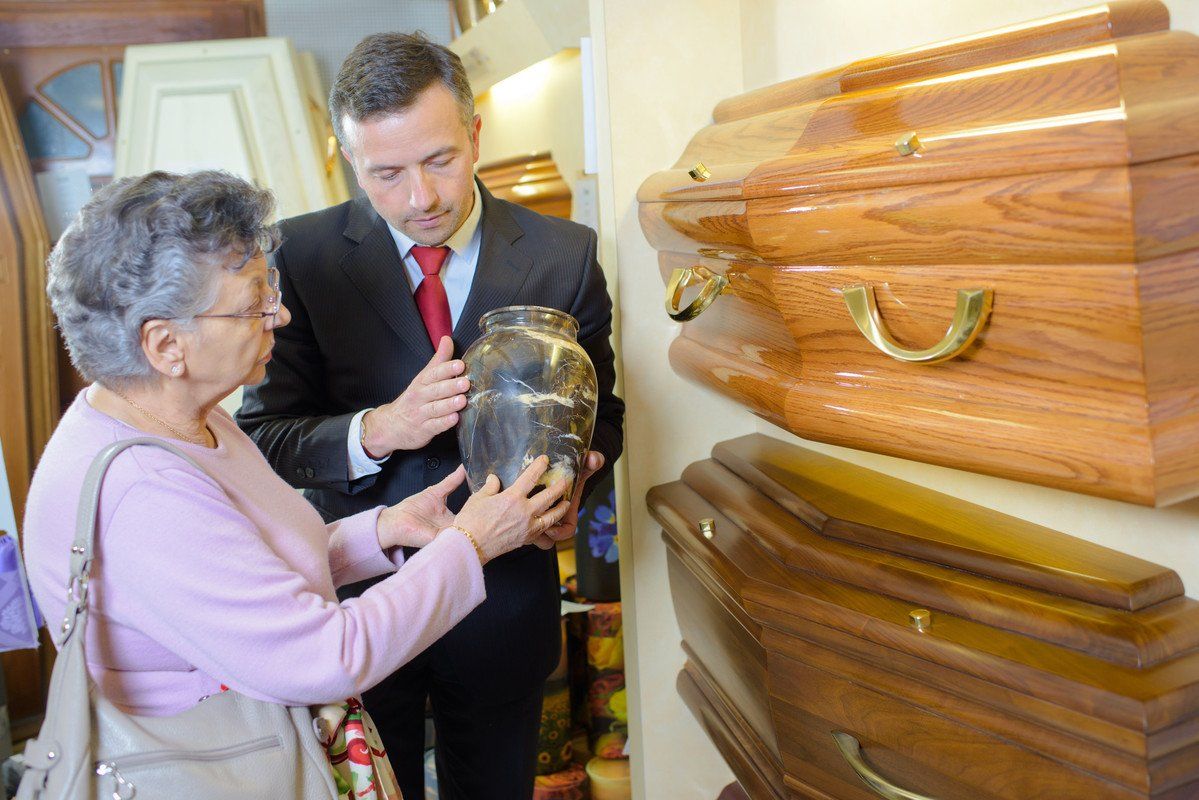 Une dame choisit une urne funéraire avec l'aide d'un professionnel