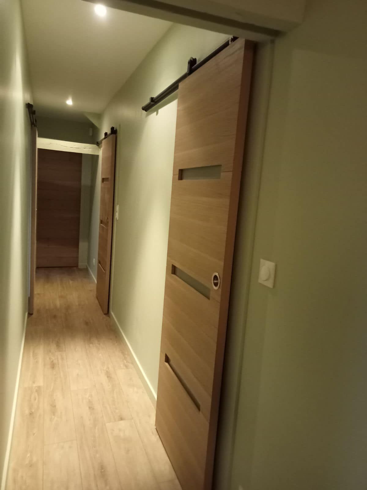 Une porte coulissante en bois installée dans un couloir.