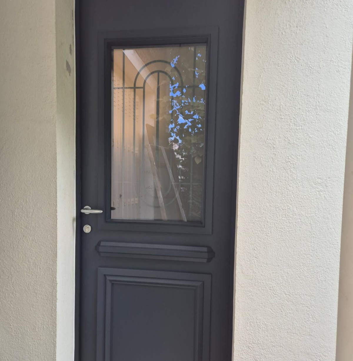 Porte d'entrée vitrée, sérigraphie visible sur la vitre.