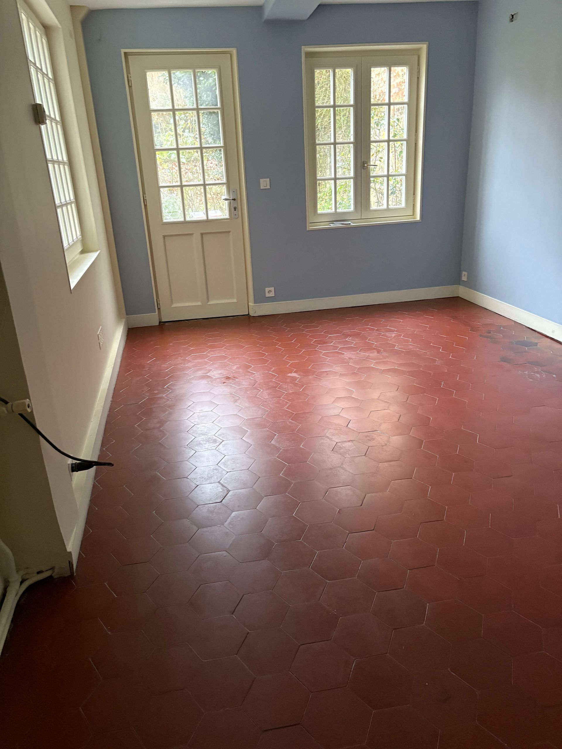 Pièce vide aux murs bleus et sol rouge.