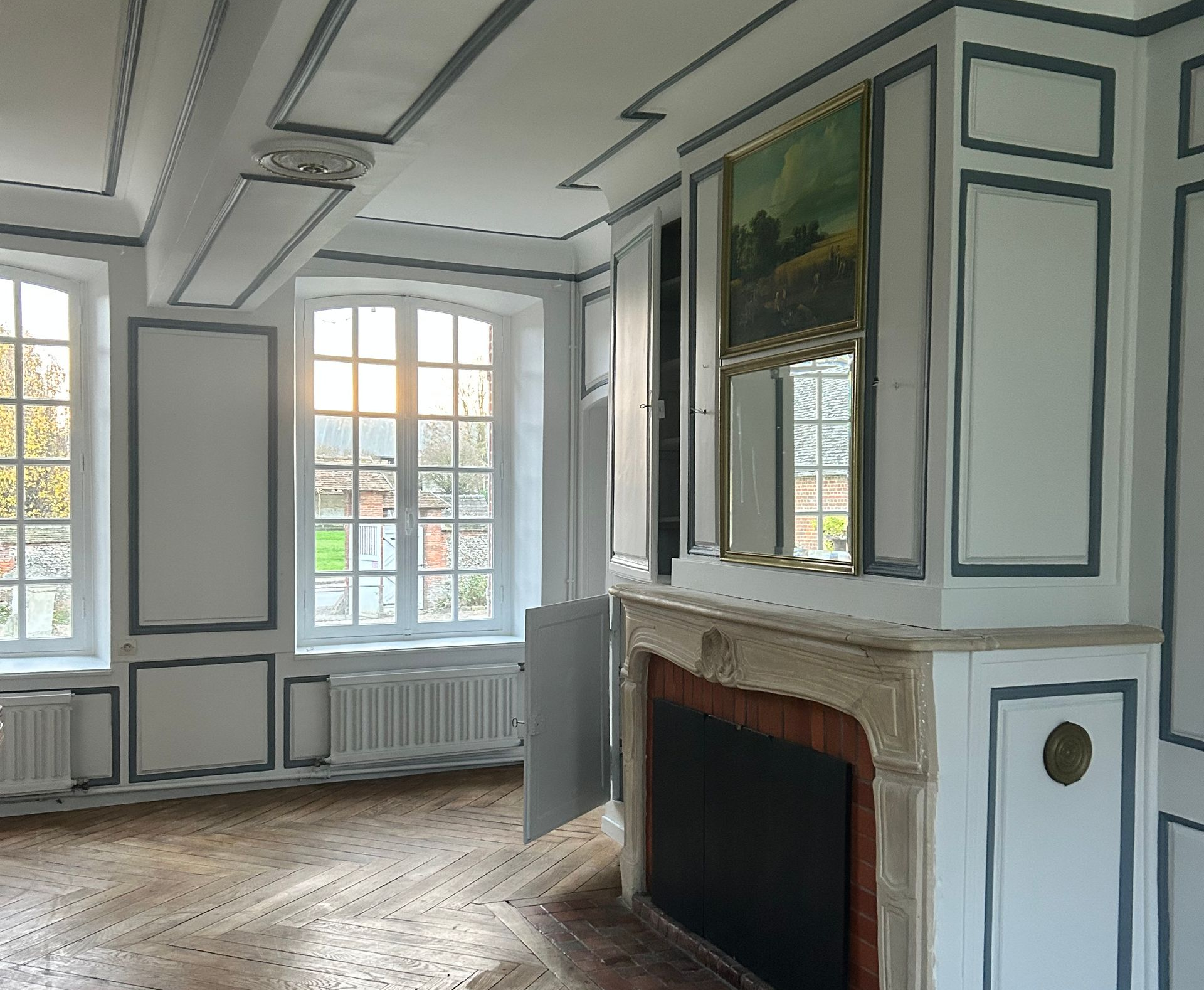 Une pièce élégante aux murs blancs, avec encadrements bleus grisés.