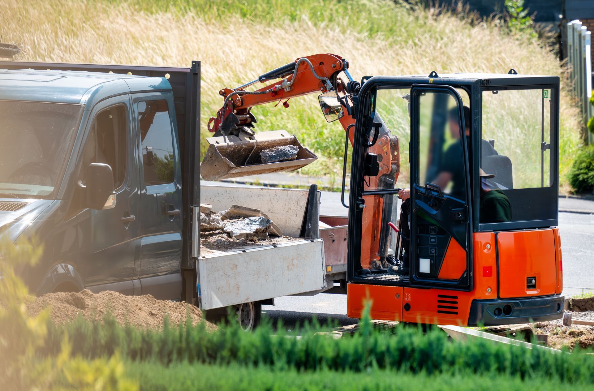 Une minipelle charge des gravats dans un camion à plateau 