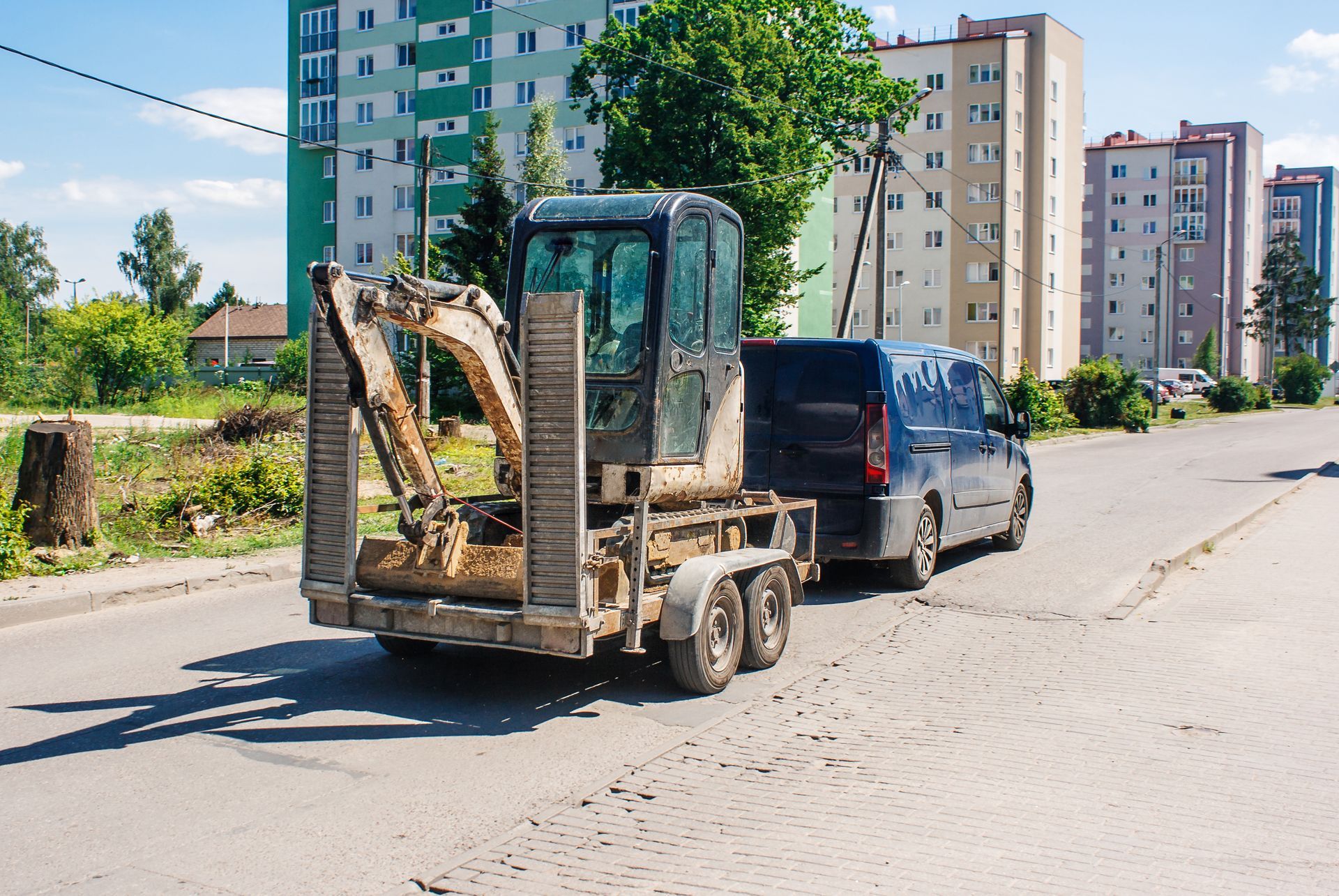 La voiture transporte une minipelle chargée sur une remorque