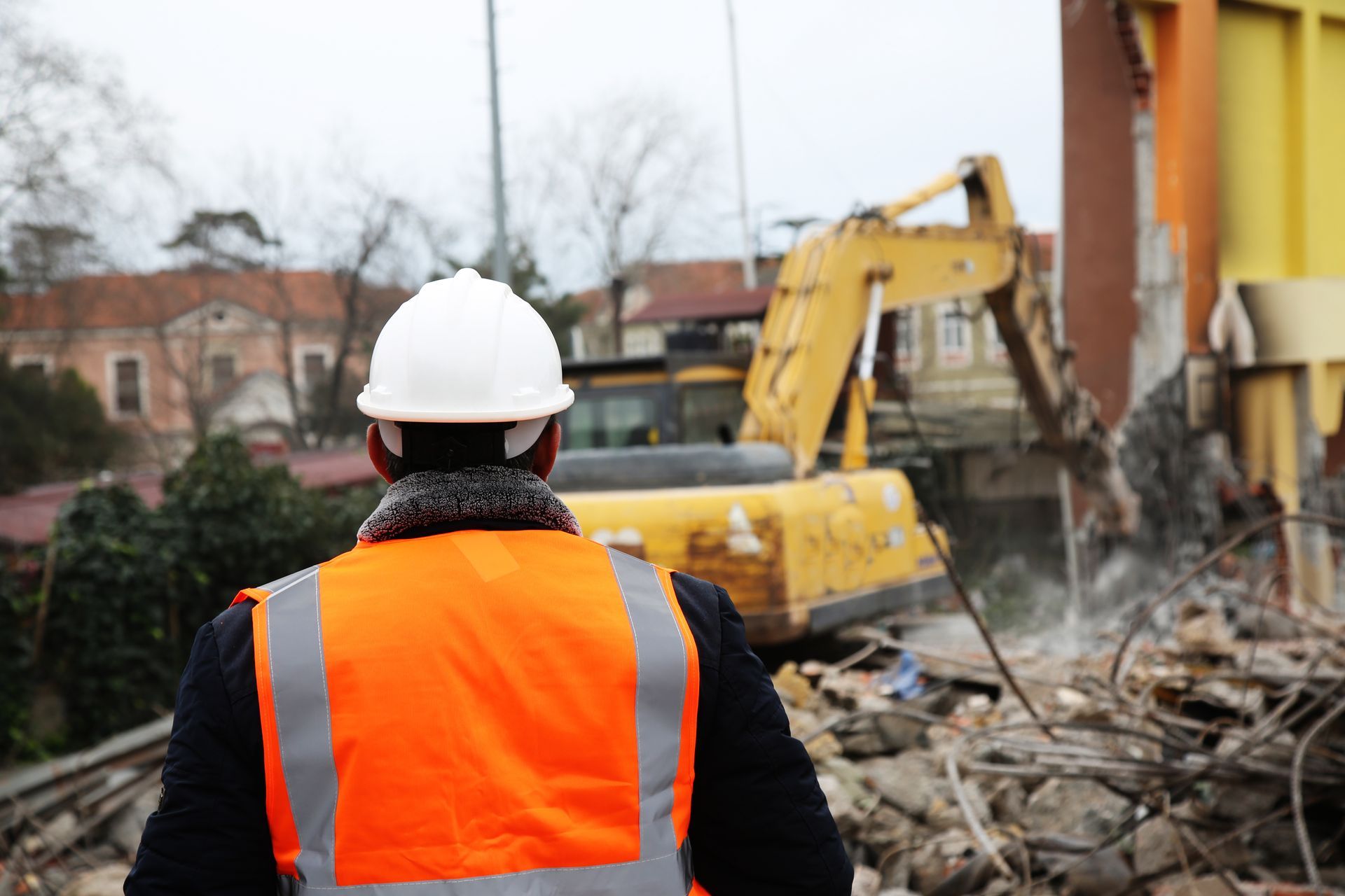 Un ingénieur, portant un casque et une veste, contrôle un chantier extérieur.