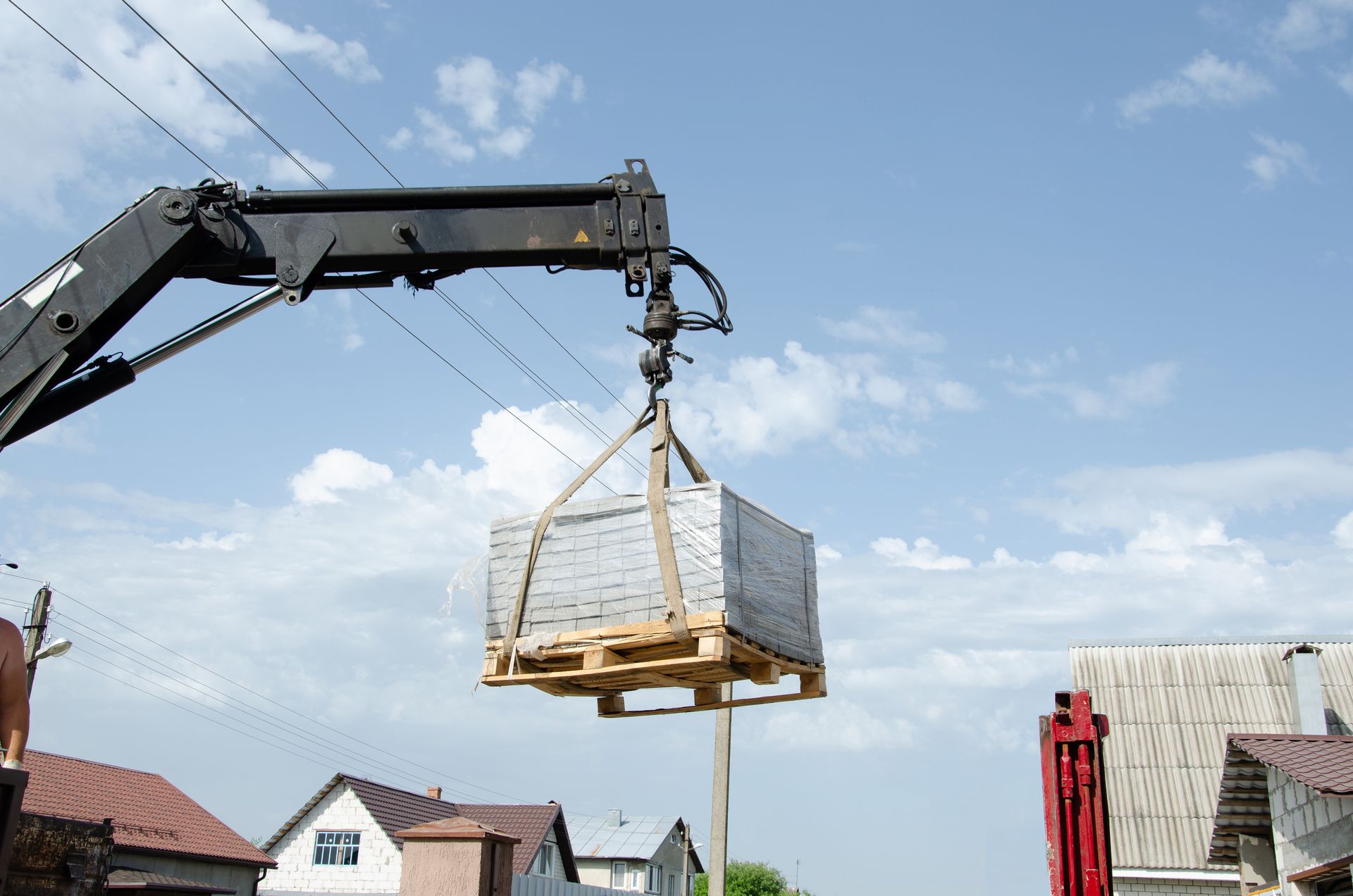 Un camion-grue décharge les tuiles dans la rue.