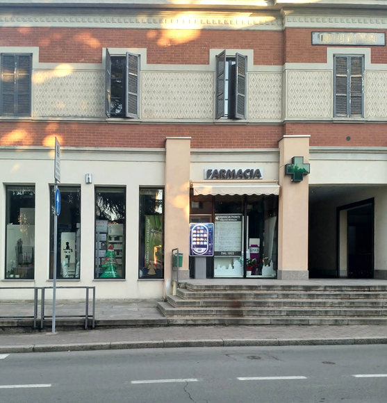 Una farmacista bionda in camice bianco prende i farmaci da uno scaffale in una farmacia ben illuminata.