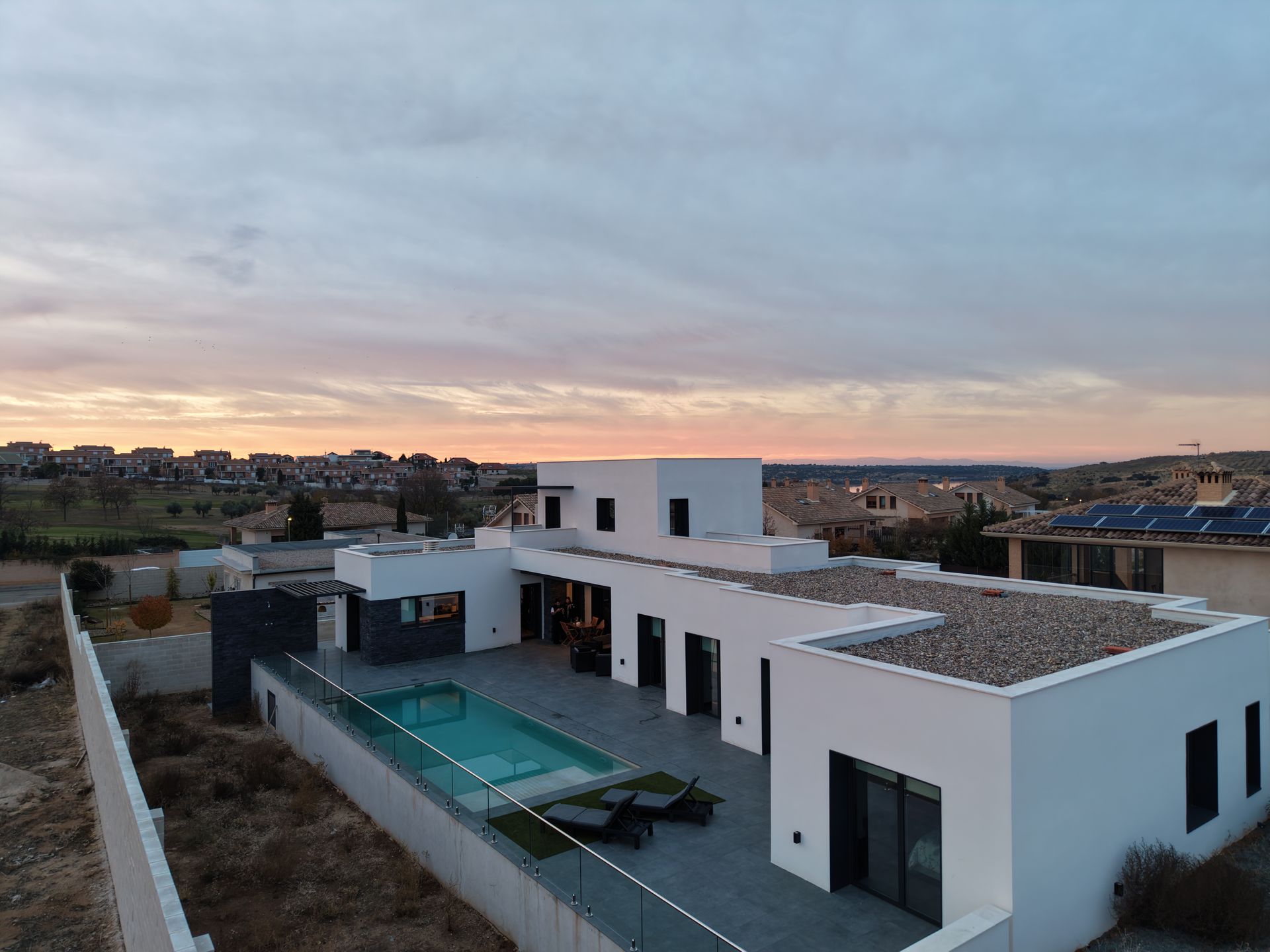 Moderna casa blanca con piscina, con vistas a un paisaje desértico al atardecer.