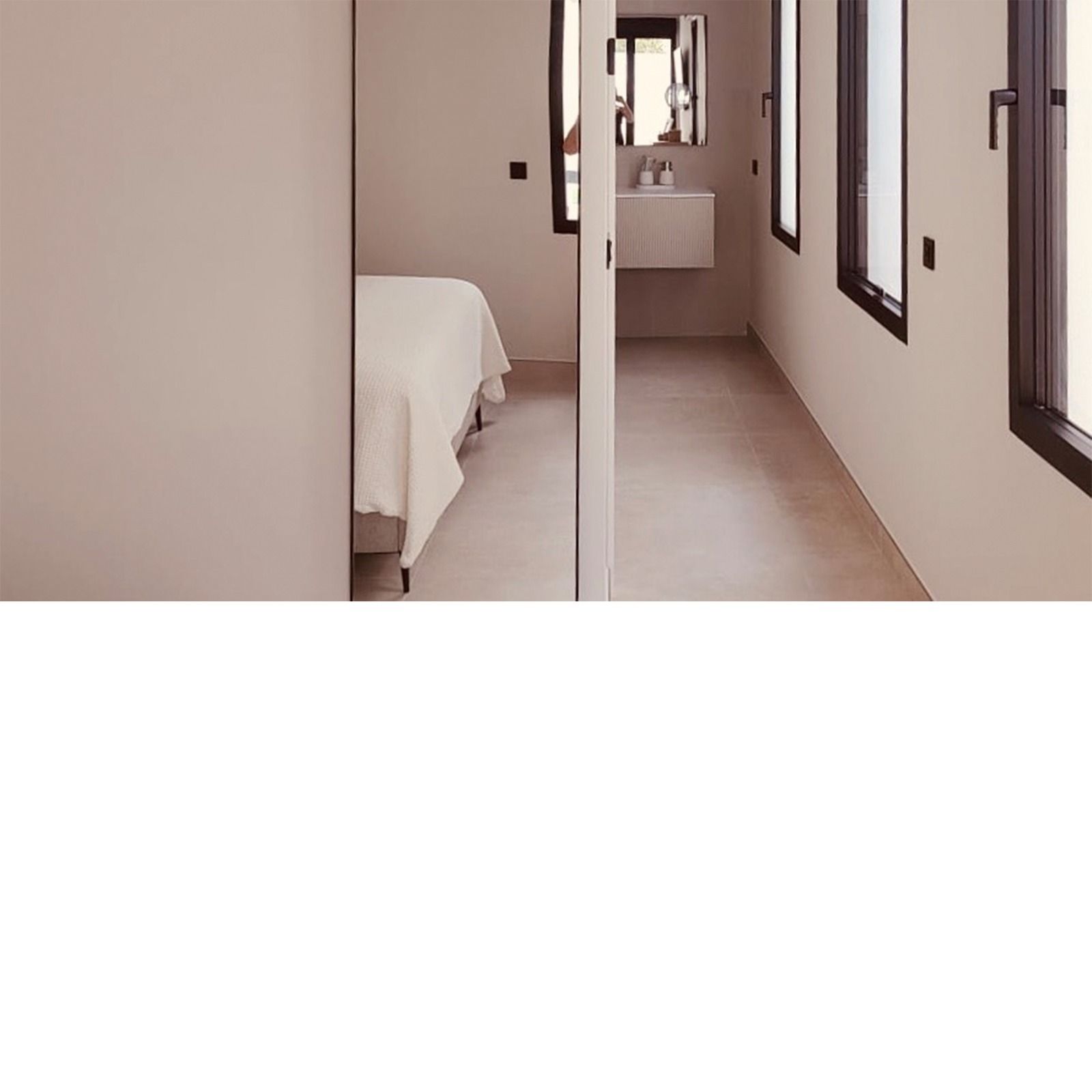 Dormitorio estrecho y baño con cama, lavabo y dos ventanas.