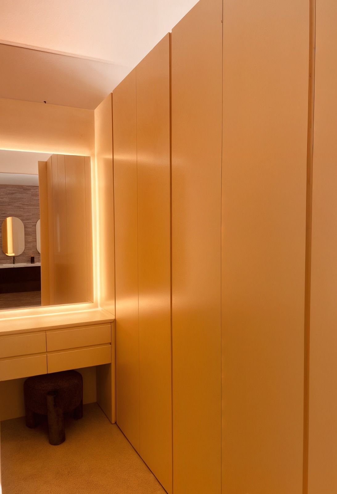 Armario con puertas de madera clara y tocador con espejo.