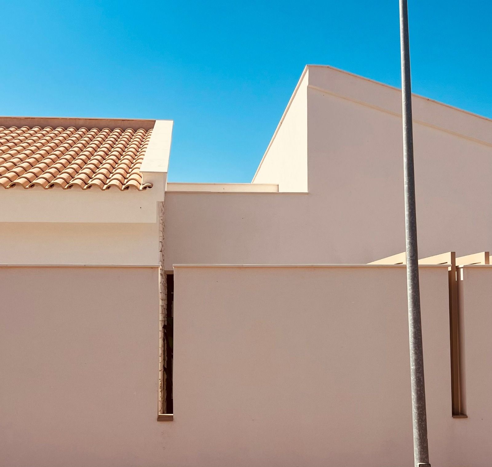 Edificios de color canela y un techo de tejas marrones contra un cielo azul claro.