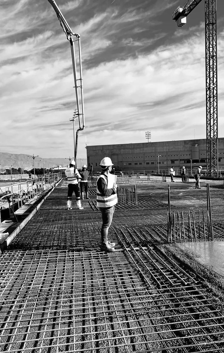 Un trabajador de la obra con chaleco de seguridad observa el vertido del hormigón.