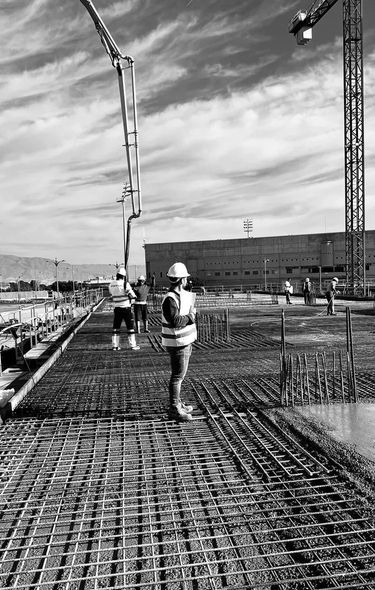 Un trabajador de la obra con chaleco de seguridad observa el vertido del hormigón.