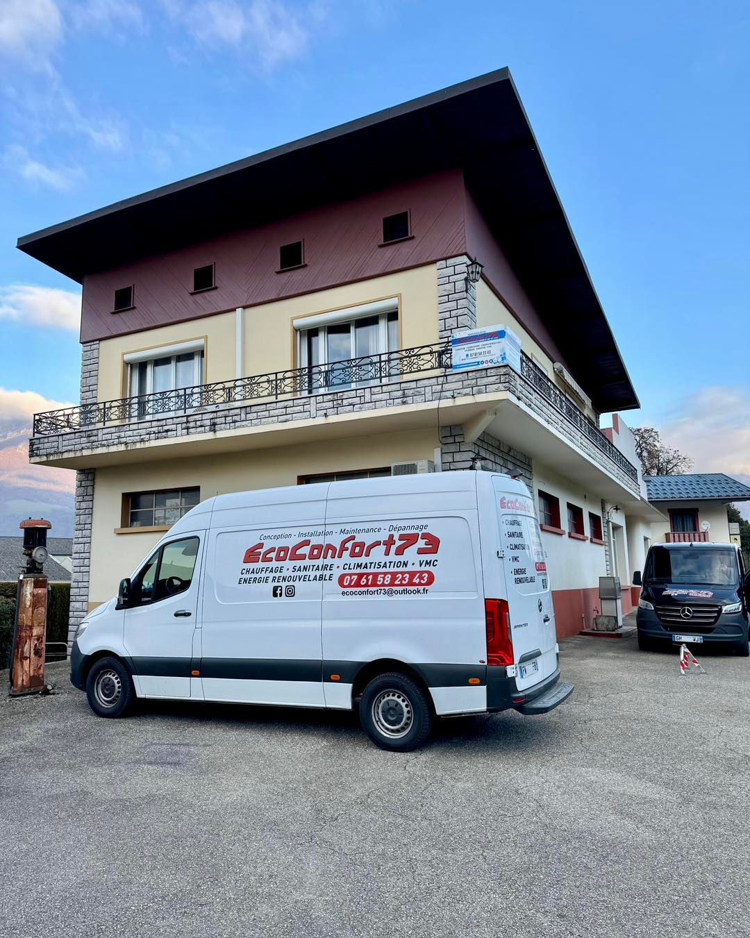 Fourgonnette blanche avec le logo EcoConfort73 garée à l'extérieur d'un bâtiment de deux étages avec des sections marron clair et marron foncé