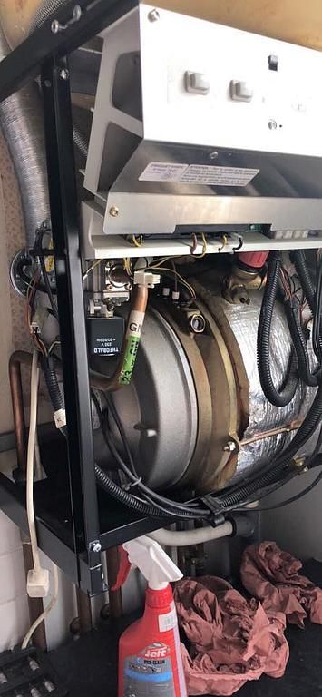 Équipement industriel avec ossature métallique, entouré de fils et d'isolant, et d'une bouteille de nettoyage.