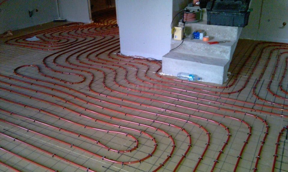 Tuyaux rouges posés sur un sol, prêts pour le béton, faisant partie d'un système de chauffage