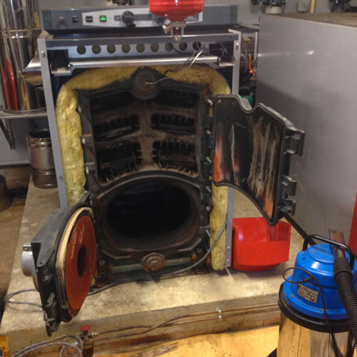 Fournaise à chaudière ouverte avec intérieur exposé, portes rouges, vide bleu et isolation jaune.