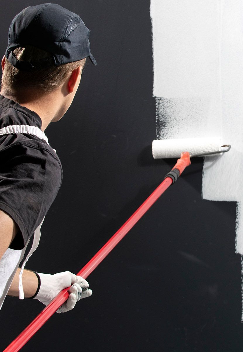 Un ouvrier repeint un mur noir en blanc