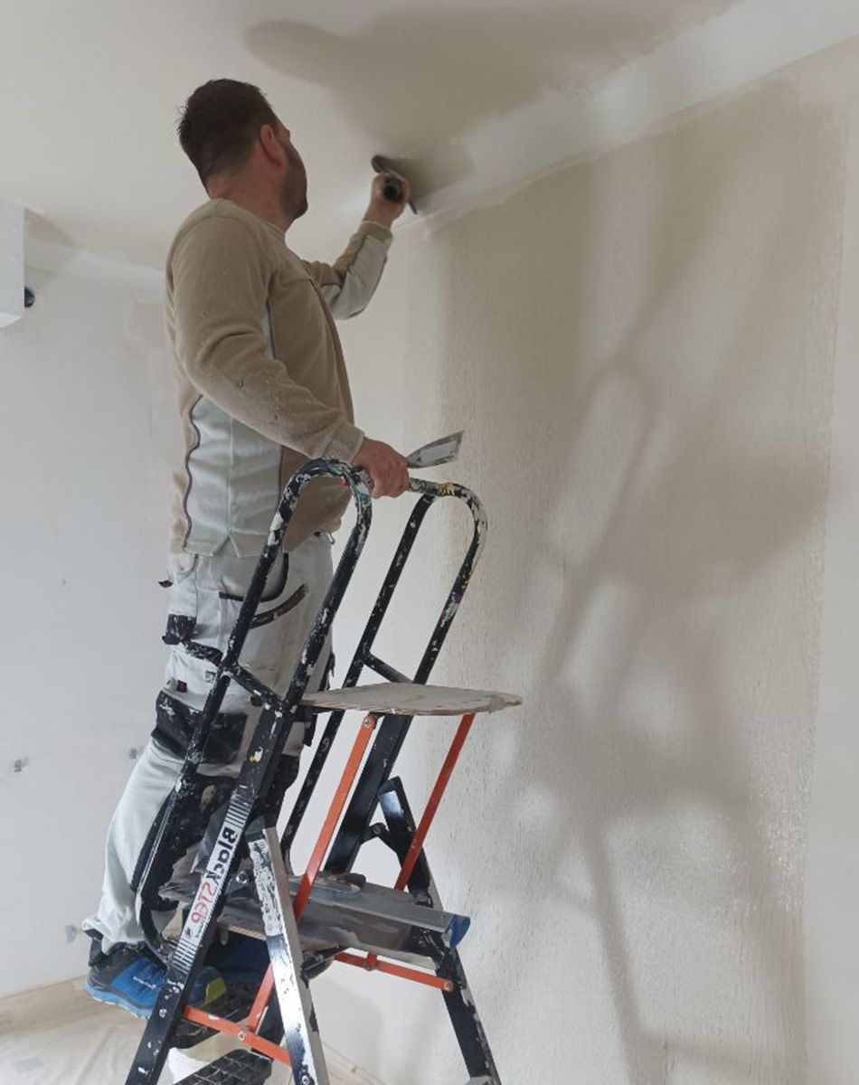 Un peintre prépare un plafond avant de le peindre