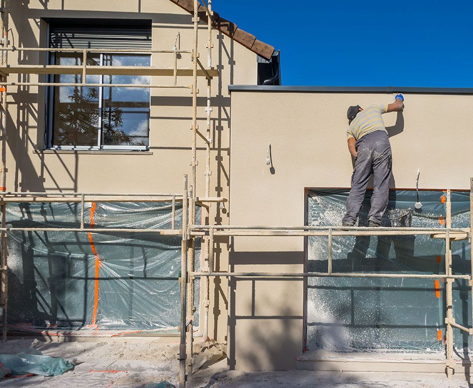 Un peintre est en train de repeindre la façade d'une maison