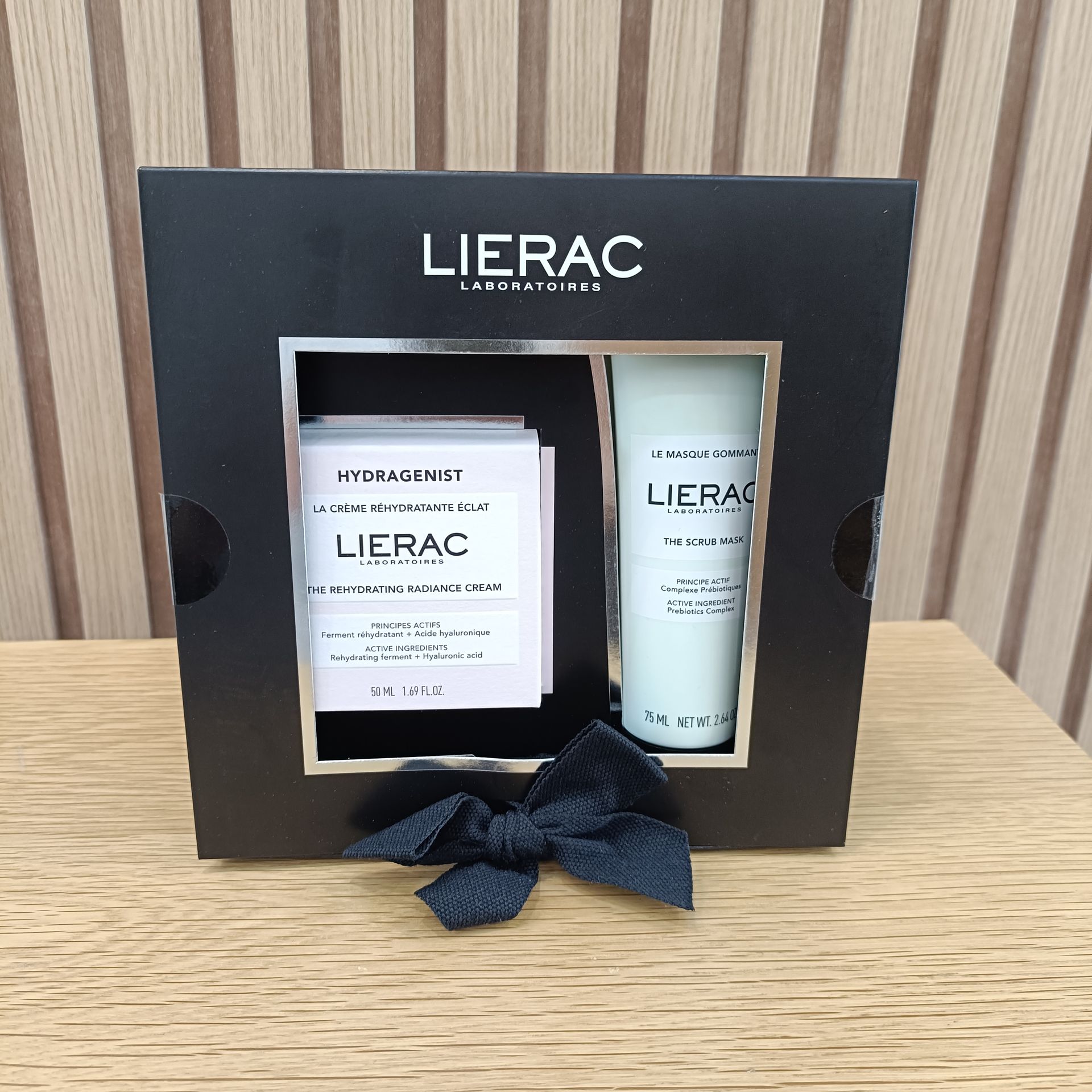 Caja de regalo negra con productos para el cuidado de la piel Lierac, que incluye un tubo de crema y sobres.