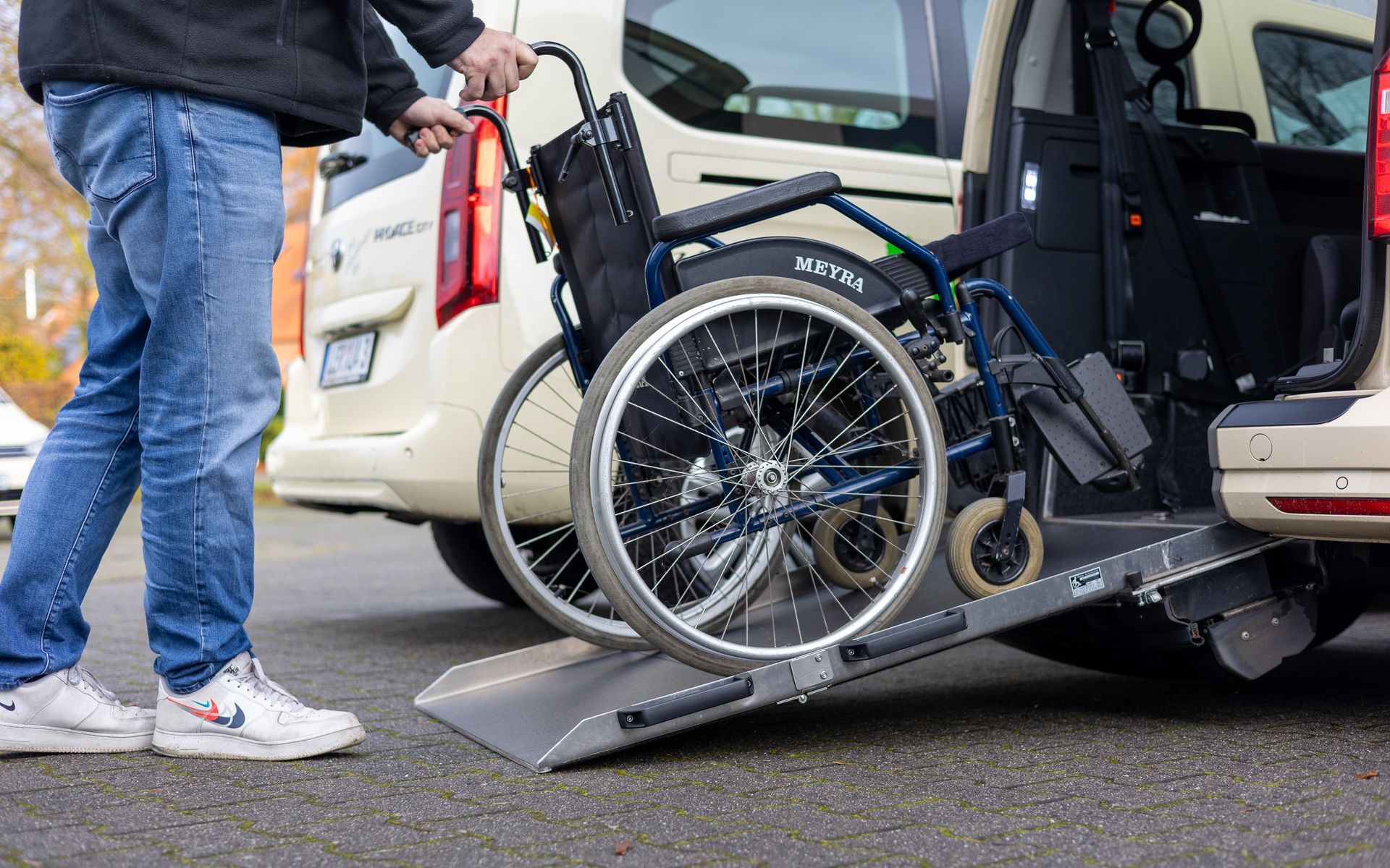 Ein Mann lädt einen Rollstuhl in den hinteren Teil eines Lieferwagens.