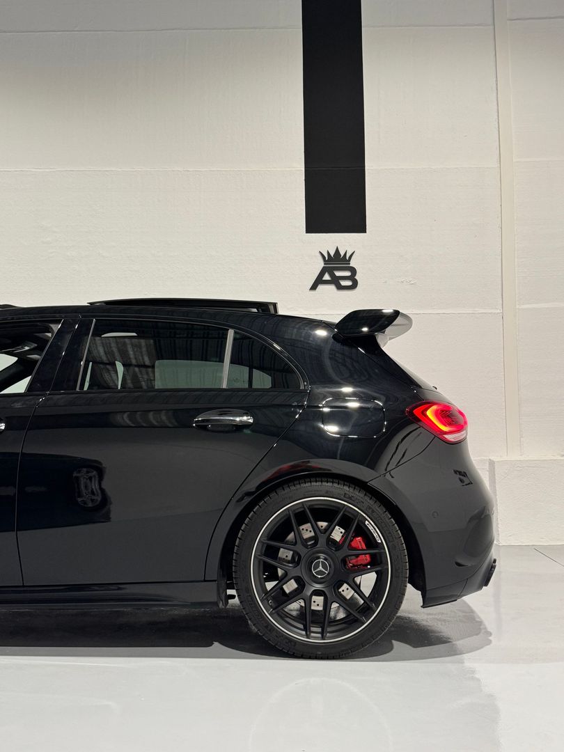 Mercedes-Benz hatchback negro, estacionado en el interior, con ruedas negras personalizadas y pinzas de freno rojas.