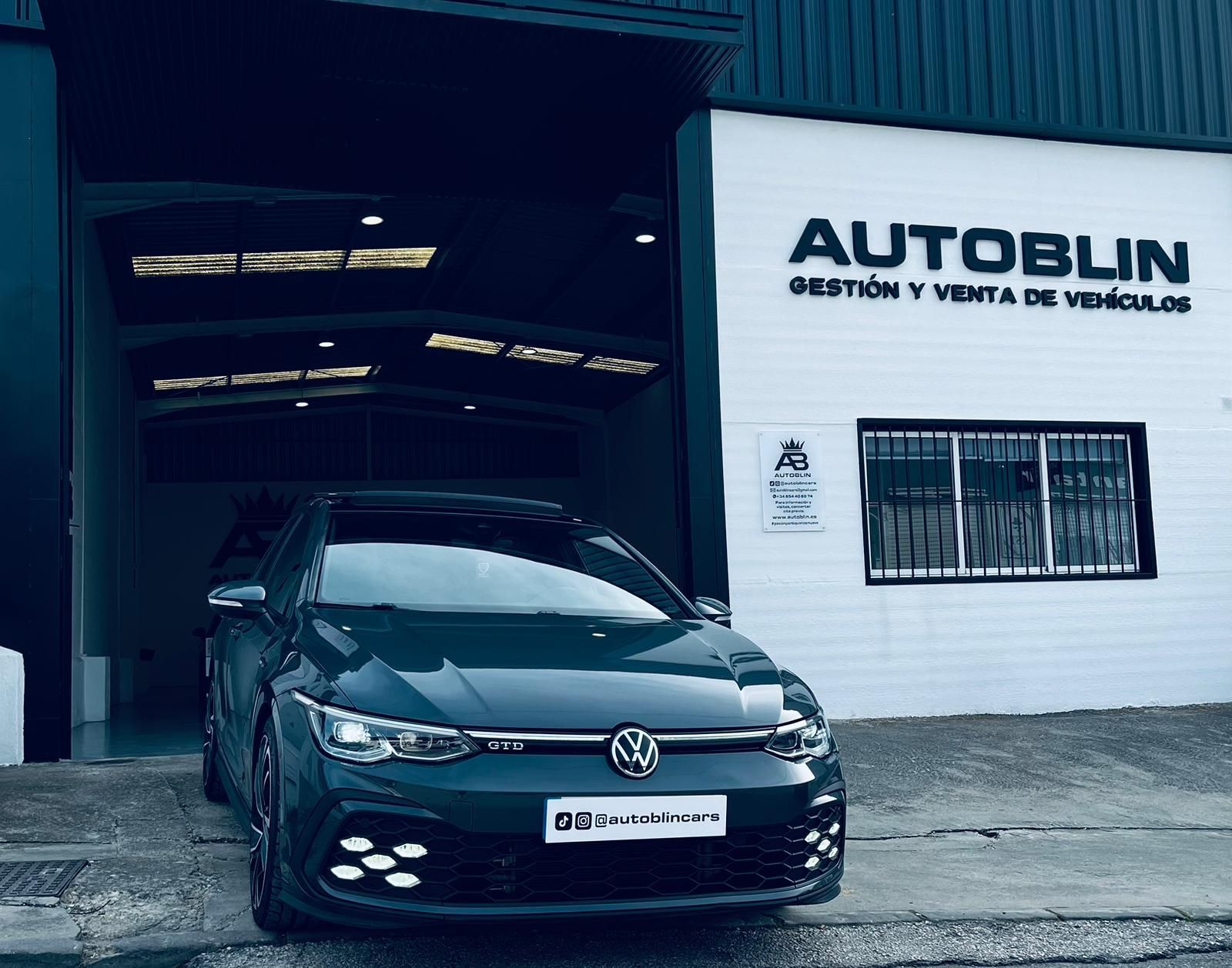 Dos mecánicos examinan el motor de un automóvil con una lista de verificación; uno señala la varilla de nivel.