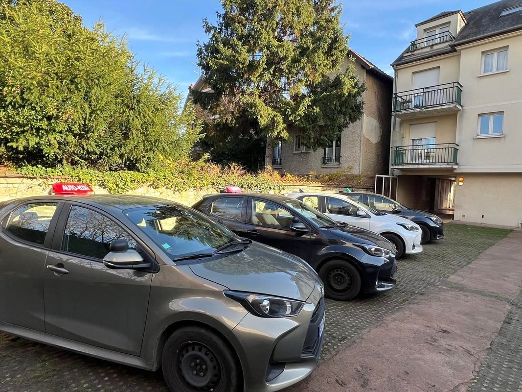 Quatre Toyota garées avec des panneaux rouges sur le toit devant un bâtiment.