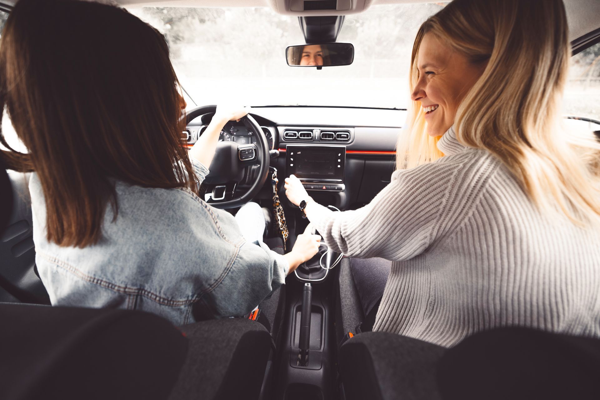 Une adolescente conduisant une voiture avec une femme plus âgée à côté