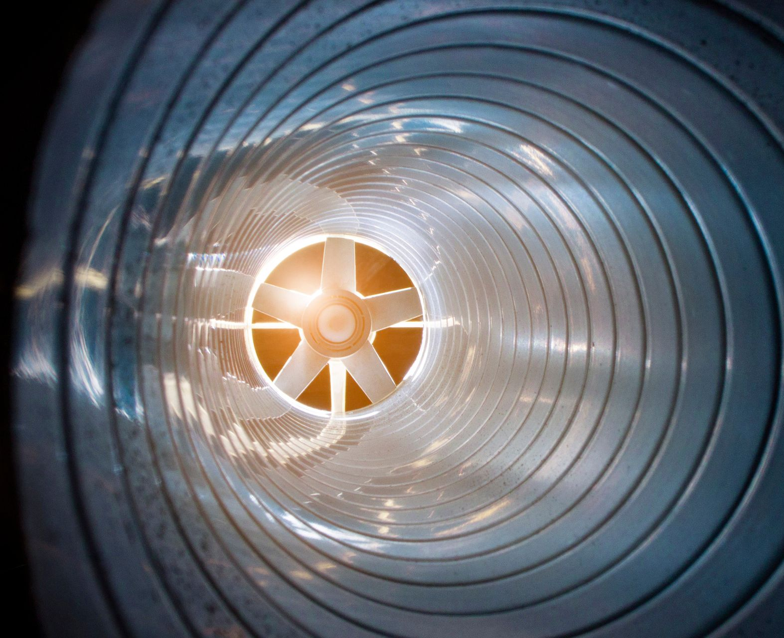 Vue intérieure d'un tube métallique en spirale muni d'un ventilateur à son extrémité.