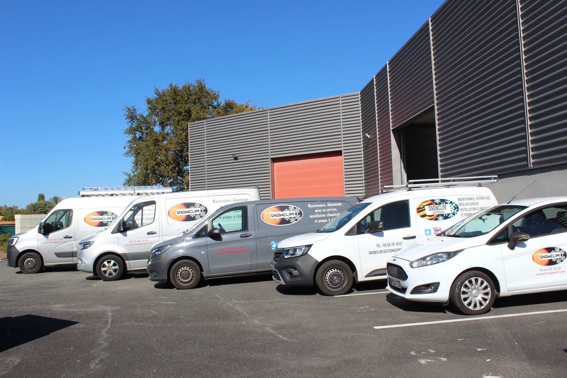 Plusieurs camionnettes blanches et grises garées devant un bâtiment.