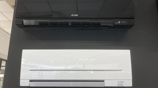 Chaudière murale blanche à côté d'un chauffe-eau bleu, reliés par des tuyaux isolés noirs.