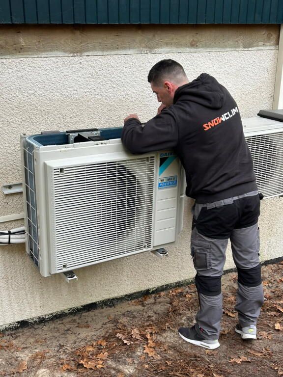 Des ouvriers installent des unités de climatisation sur un toit.