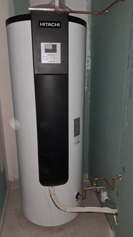 Évier blanc rempli d'eau bouillante, robinet chromé, comptoir en marbre, meuble sombre.