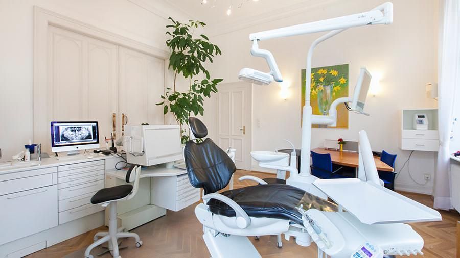 Eine Zahnarztpraxis mit einem schwarzen Stuhl und einem Computer