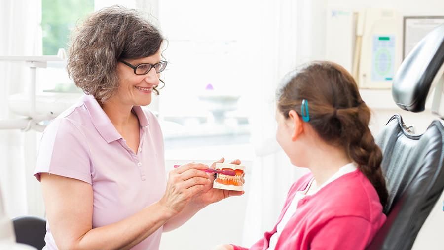 Eine Frau hält ein Modell der Zähne eines Kindes.